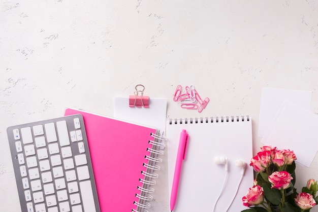 Top view of notebooks on desk with bouquet of roses and copy space