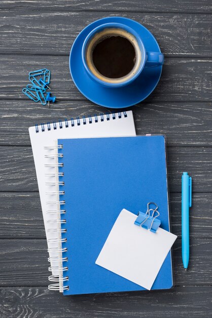 Top view of notebooks on wooden desk with coffee cup and pen