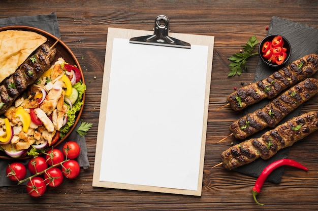 Free Photo top view of notepad with delicious kebabs and tomatoes