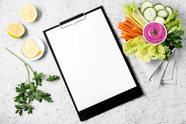 Top view of notepad with plate of vegetables and lemon