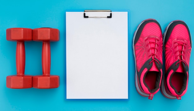 Top view of notepad with weights and sneakers