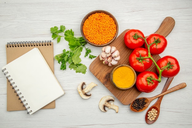 Free photo top view notepads garlic turmeric tomatoes on wood serving board