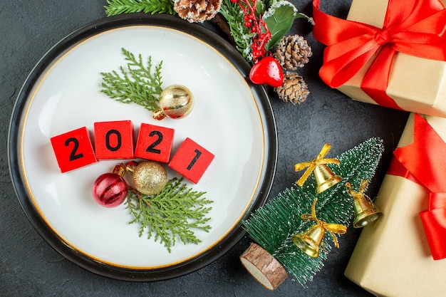 Top view of numbers decoration accessories on a plate fir branches conifer cone christmas tree on dark background