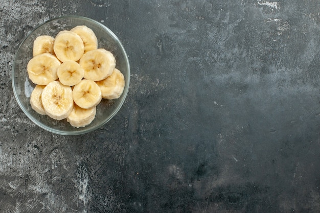 Free photo top view nutrition source fresh bananas chopped in a glass pot knife on gray background