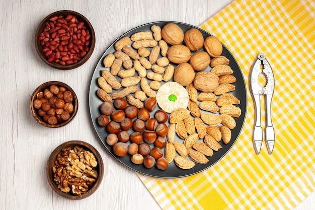 Top view nuts composition fresh walnuts peanuts and hazelnuts inside plate on the white desk nut tree snack plant many shell