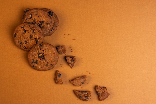 Free photo top view of oatmeal cookies with chocolate chips falling broken with copy space on ocher