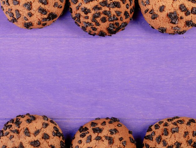 Top view of oatmeal cookies with chocolate on purple wooden background with copy space