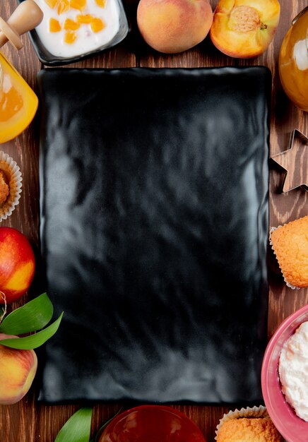 Top view of oblong plate with cottage cheese and peach cupcake around on wooden surface