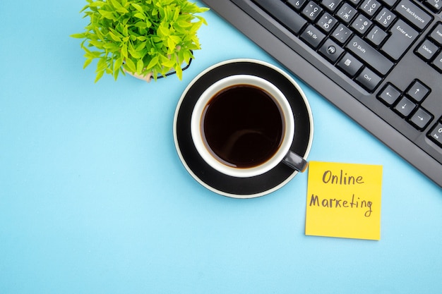 Free Photo top view of office concept with a cup of black tea and online marketing writing flower on blue background