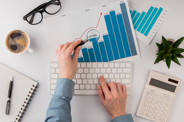 Free Photo top view of office desk with growth chart analyzed with magnifying glass