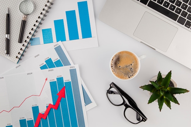 Free photo top view of office desk with growth chart and coffee with glasses