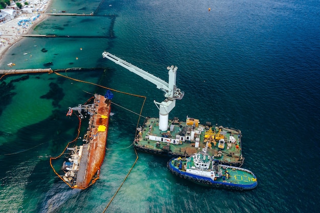 Top view of an old tanker that ran aground and overturned on the shore near the coast