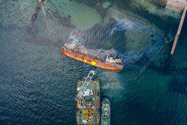 Top view of an old tanker that ran aground and overturned on the shore near the coast.