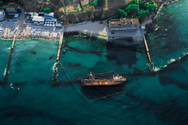 Top view of an old tanker that ran aground and overturned on the shore near the coast.