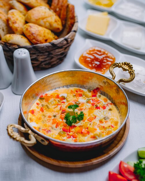 Top view omelet with vegetables in a pan with a basket of bread