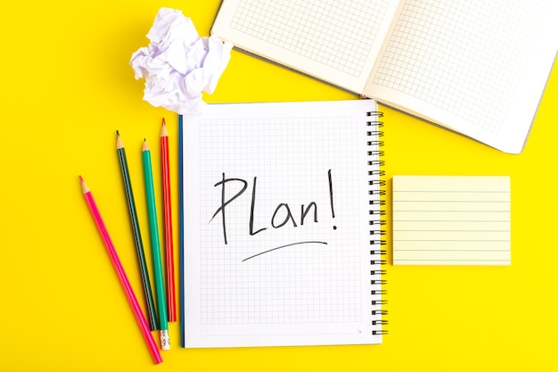 Top view open copybook with colorful pencils on yellow desk