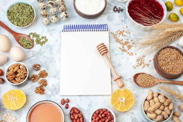 Top view open notepad with eggs flour jelly different nuts and seeds on white nut color cake sweet pie photo sugar dough