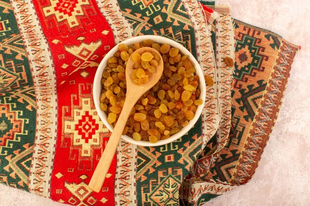 Free Photo a top view orange dried raisins inside round plate on colorful designed carpet on pink