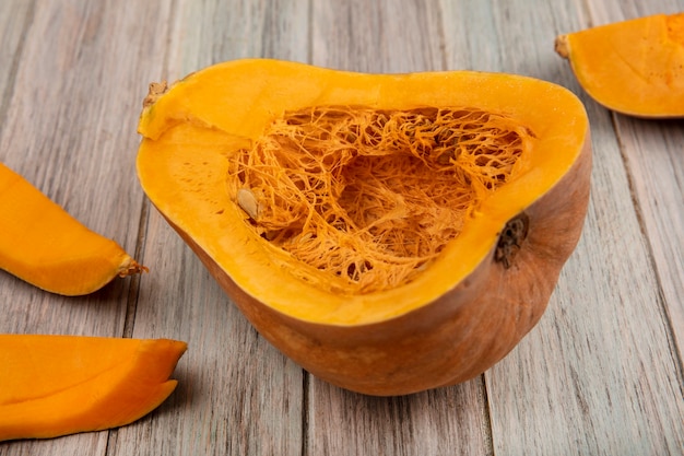 Top view of orange nutritious pumpkin with its seeds with pumpkin peels isolated on a grey wooden surface