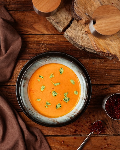 A top view orange soup with leaves on the wooden desk food meal