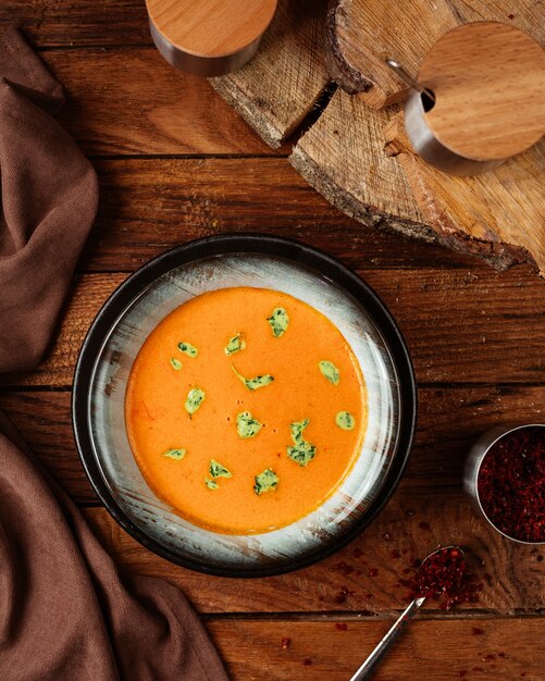 Free Photo a top view orange soup with leaves on the wooden desk food meal