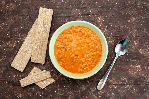 Free photo top view orange tasty soup with crackers and spoon on brown, food meal dinner soup