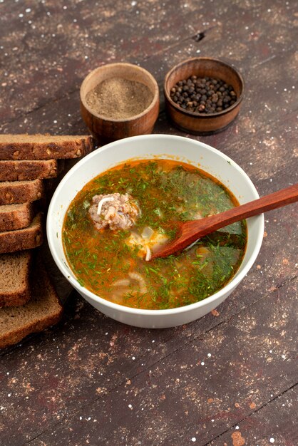 Top view orange vegetable soup with bread loafs greens and garlic on brown, food meal soup bread