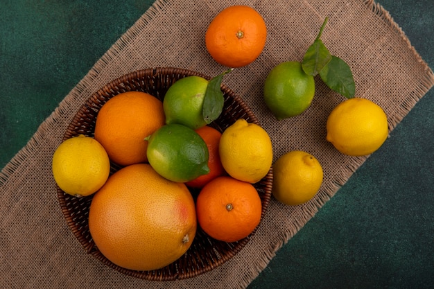 Free Photo top view oranges with grapefruit  lemons and limes in a basket on a beige napkin