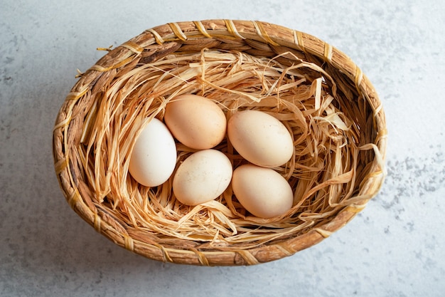 Top view of organic chicken eggs in basket over grey surface. 