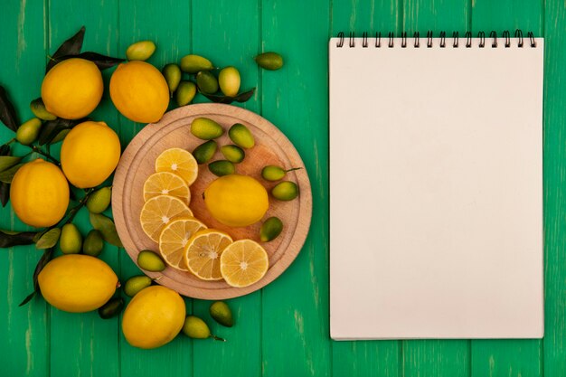 Top view of organic lemons on a wooden kitchen board with kinkans and lemons isolated on a green wooden wall with copy space