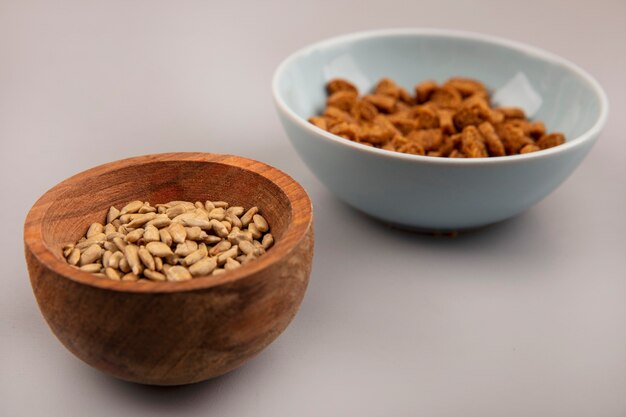 Top view of organic shelled sunflower seeds on a wooden bowl with tasty rye rusks on a bowl