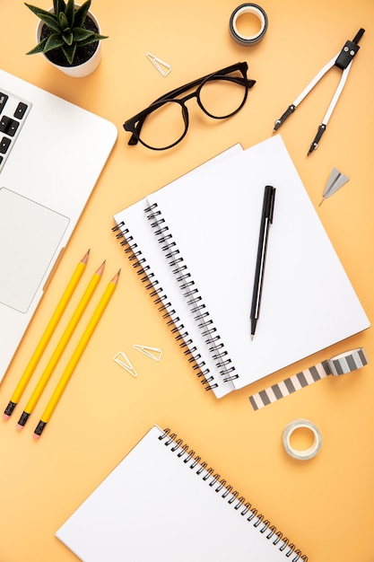 Top view organised arrangement of desk elements on orange background