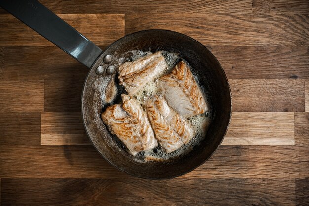 Top view of a pan with roasted meat on a wooden table