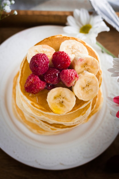 Free photo top view pancake tower with banana and raspberries