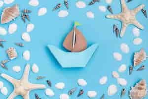 Free photo top view of paper boat with starfish and sea shells