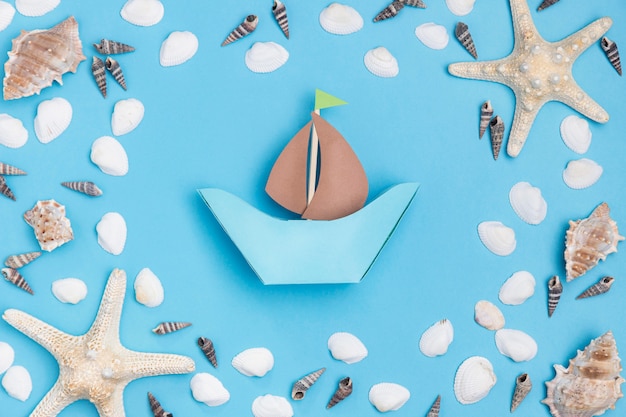 Top view of paper boat with starfish and sea shells