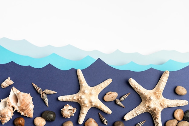 Free photo top view of paper ocean waves with starfish and sea shells