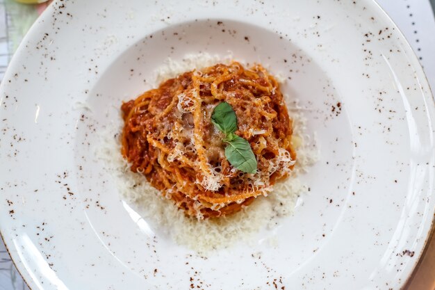 Top view pasta bolognese with grated cheese in a plate