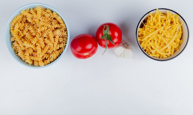 Top view of pasta in bowls and tomatoes