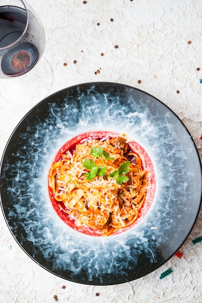 Free Photo top view pasta with meet and glass of wine in round plate