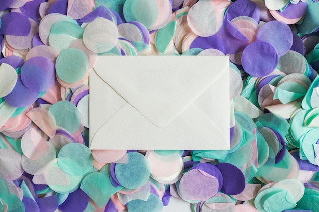 Free photo top view pastel color confetti with envelope in the middle