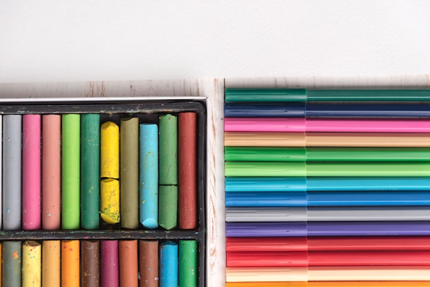 Top view of pastel paint and markers in boxes on table