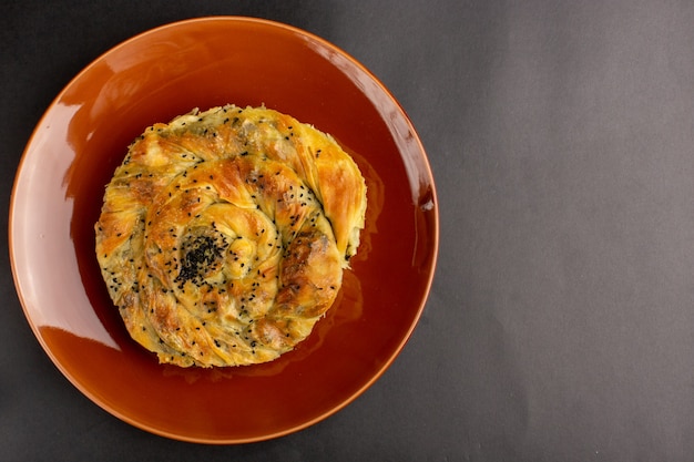 Top view of pastry with meat delicious dough meal inside brown plate on dark surface