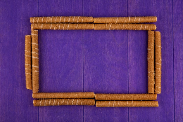 Free photo top view of pattern of crispy sticks set in square shape on purple background with copy space