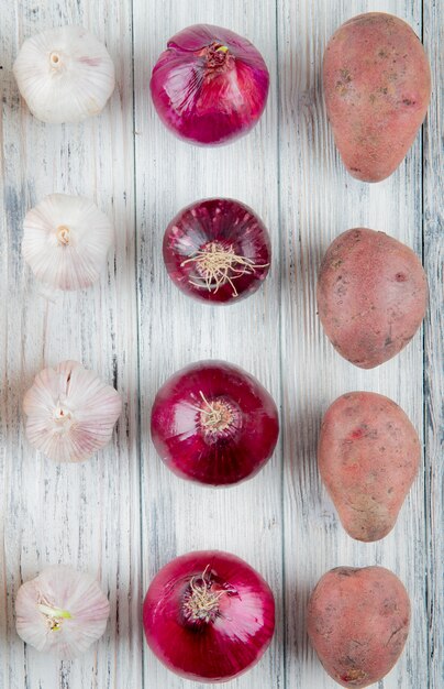 Top view of pattern of vegetables as garlic red onion potato on wooden background