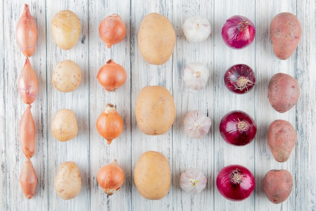 Top view of pattern of vegetables as shallot onion potato garlic on wooden background