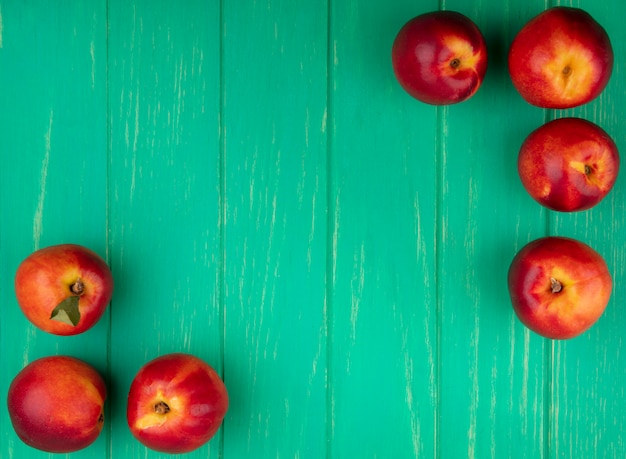 Free photo top view of peaches on a green surface