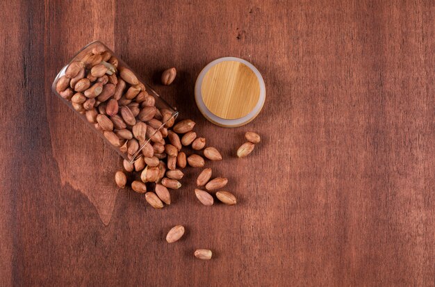 Top view peanuts in glasses with copy space on brown 