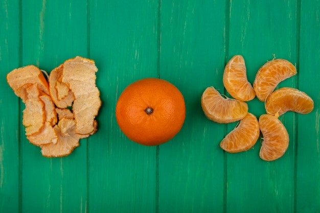 Free Photo top view peeled orange wedges with peel on a green background