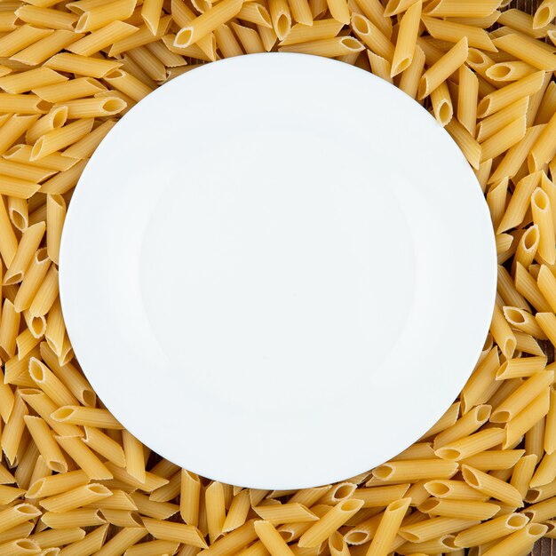 Top view penne pasta with copy space on wooden background